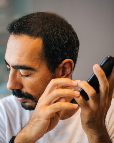 Man with refractive error using adaptive technology screen reading software on cell phone accessible