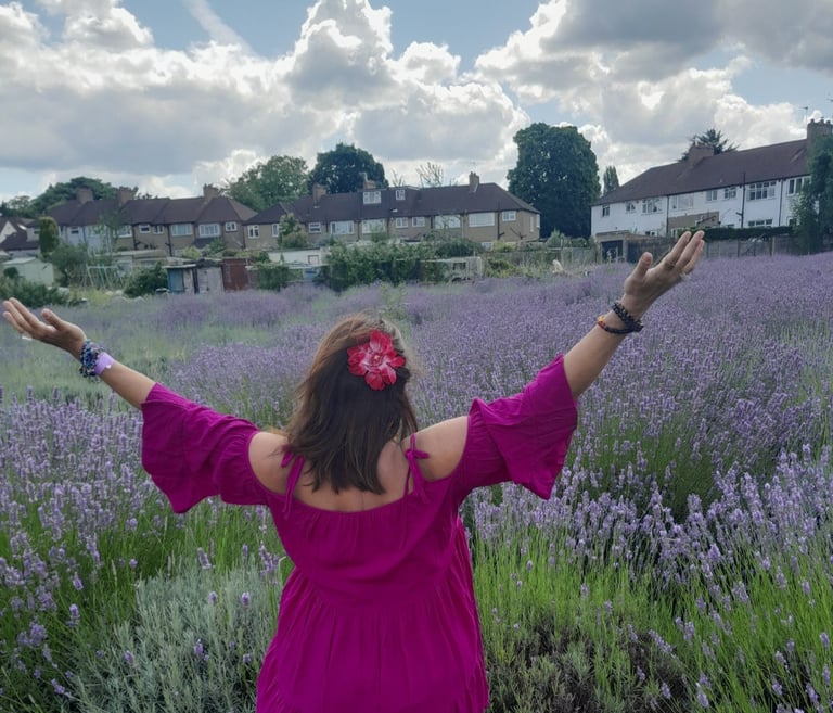 Image of the back of Sheila Cristina in a lavender field in London. In the distance is houses.
