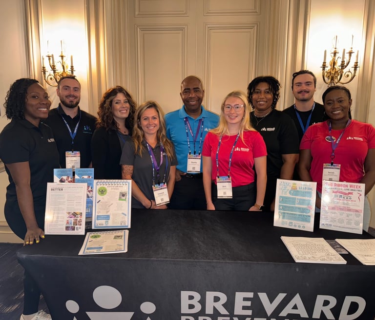 a group of people standing around an information booth smiling
