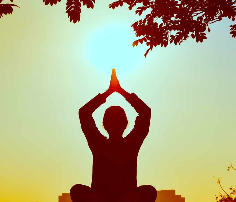 A person standing outdoors with their hands clasped overhead in a gesture of reverence or gratitude.