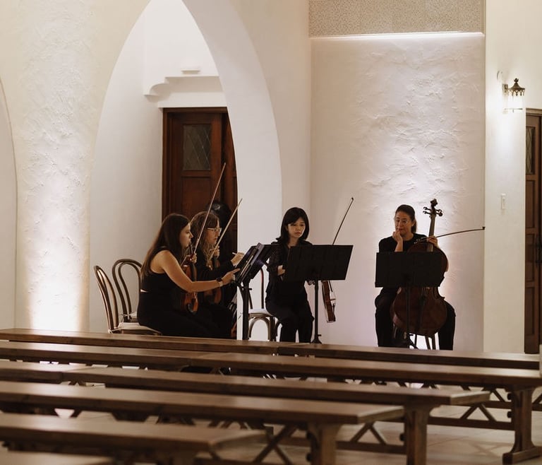 Professional string quartet performing live music for a wedding ceremony in a chapel.