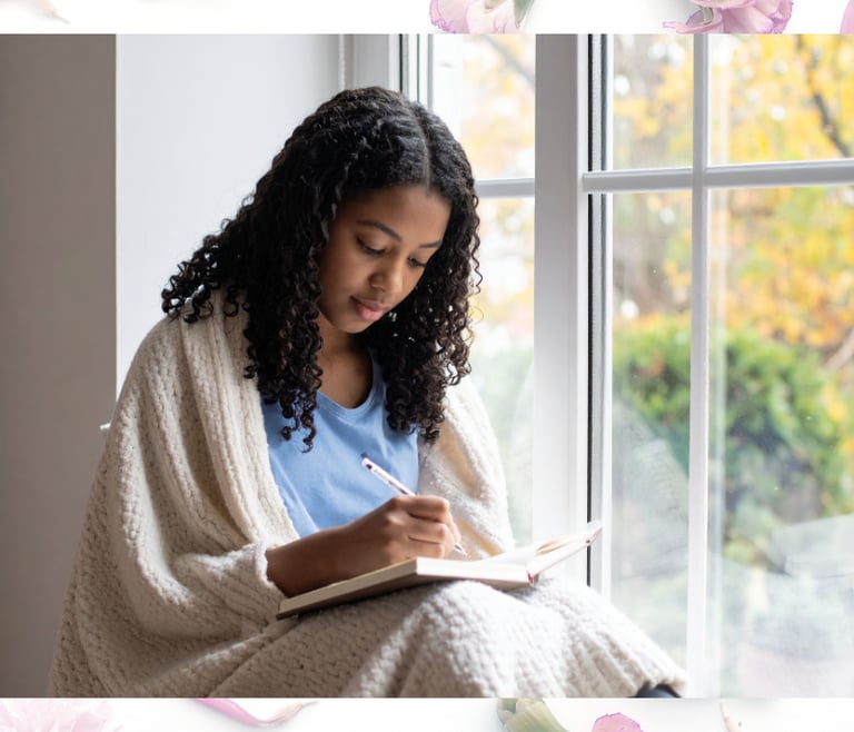 Teenage girl wrapped in a blanket journaling by a window, showing a calm self-care moment.