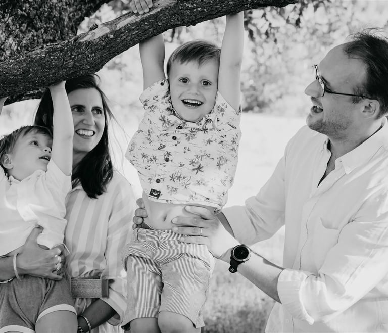 Enfants jouant à se suspendre à un arbre avec l’aide de leurs parents – séance photo de famille Gard