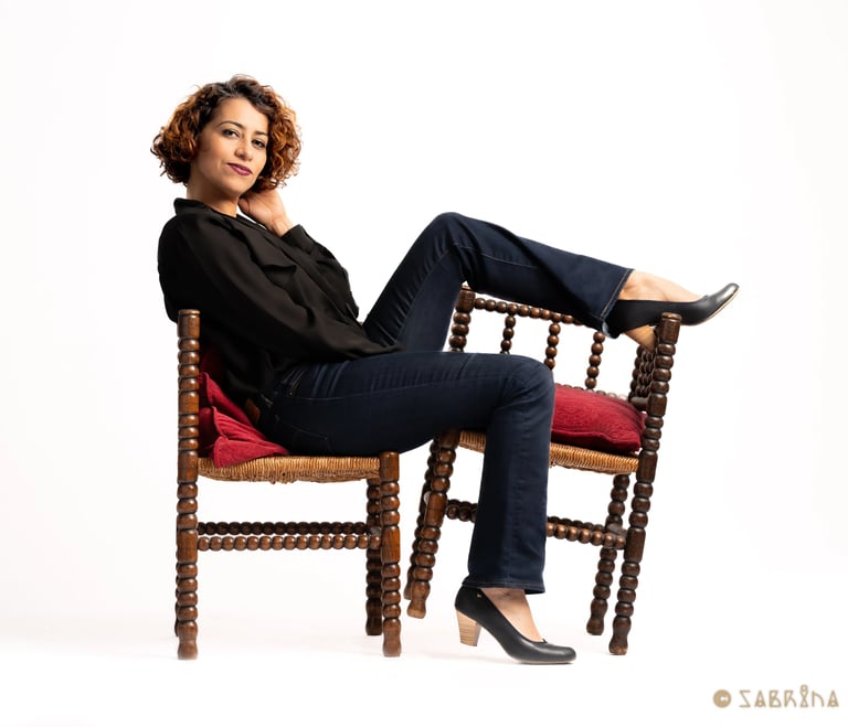 a woman sitting on a chair, pushing a chair with her leg