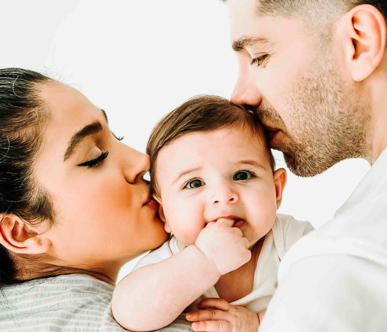 Parents kissing baby during family photoshoot – Fred Art Studio session