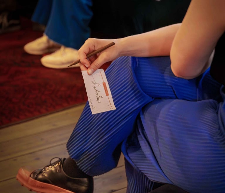 Woman holding a note and pen during workshop, writing feedback about public speaking of other women.