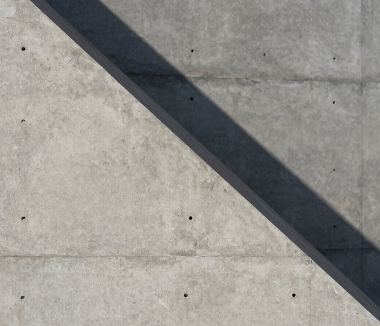 Extreme close-up of concrete architectural geometry, sharp diagonal shadow cast by hard midday sun, minimalist concrete wall texture.
