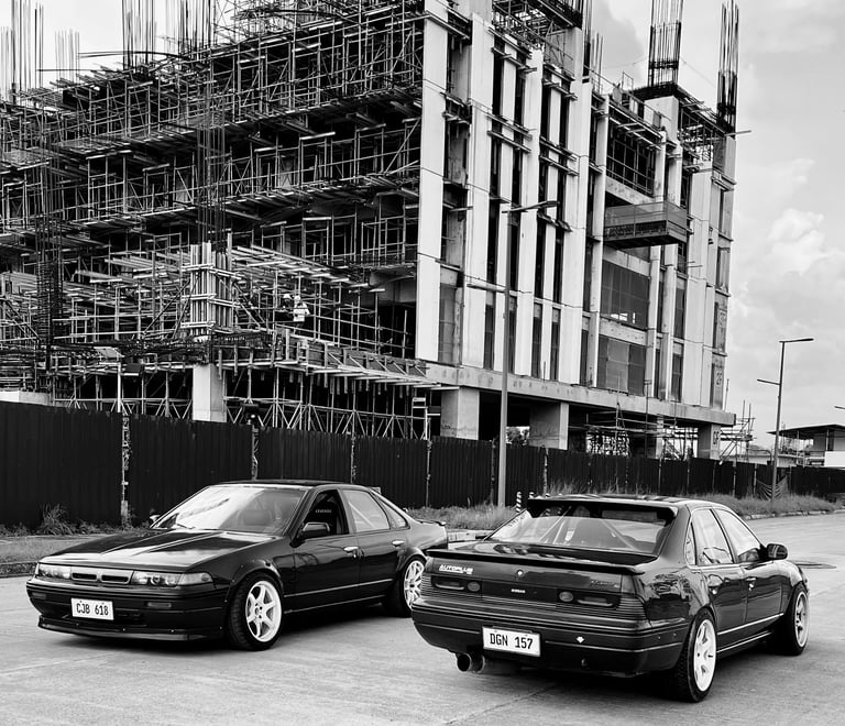 Nissan A31 cars parked on the road with scaffolding in the background
