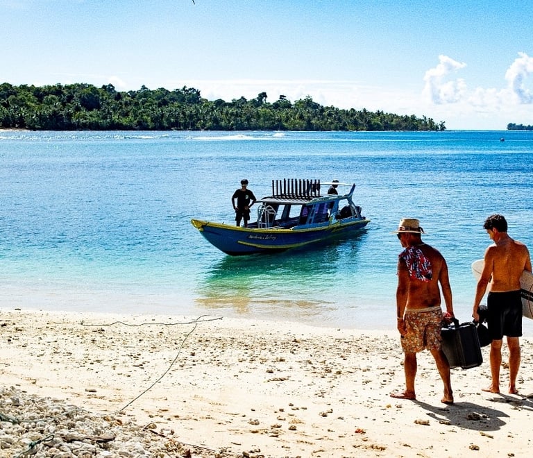 two men walking on the beach with a boat in the background