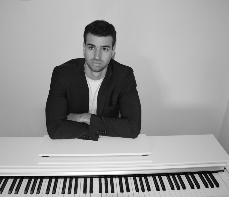 a man in a suit and tie sitting at a piano
