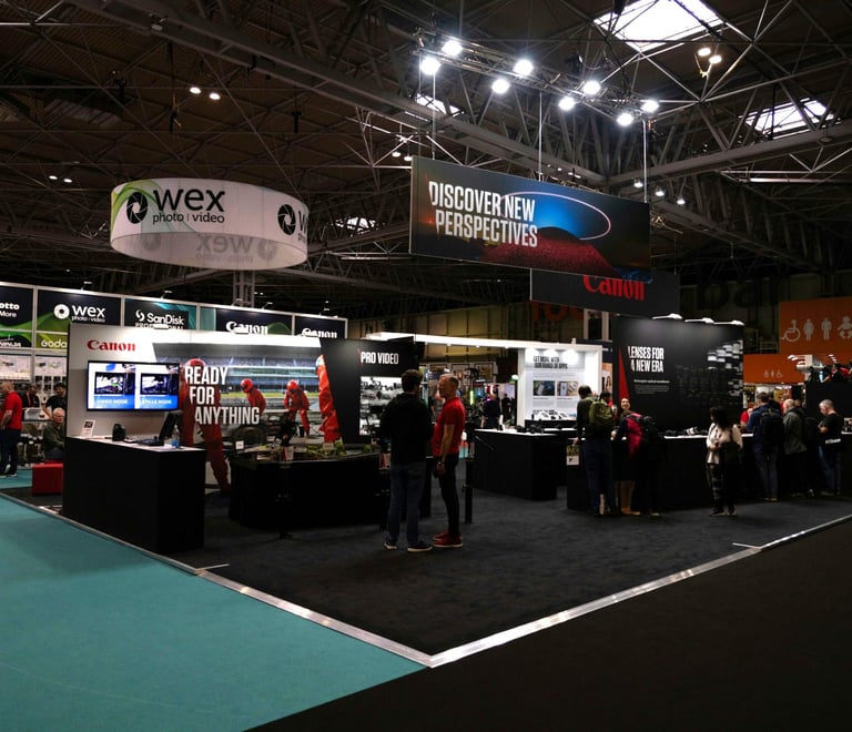 Professional camera equipment display at a Wex Photo Video convention booth with Canon and Manfrotto signage.