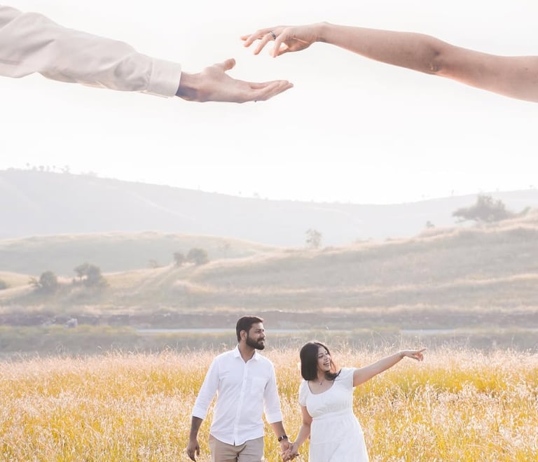 Couple holding hands in a sunlit meadow during an outdoor engagement photoshoot.