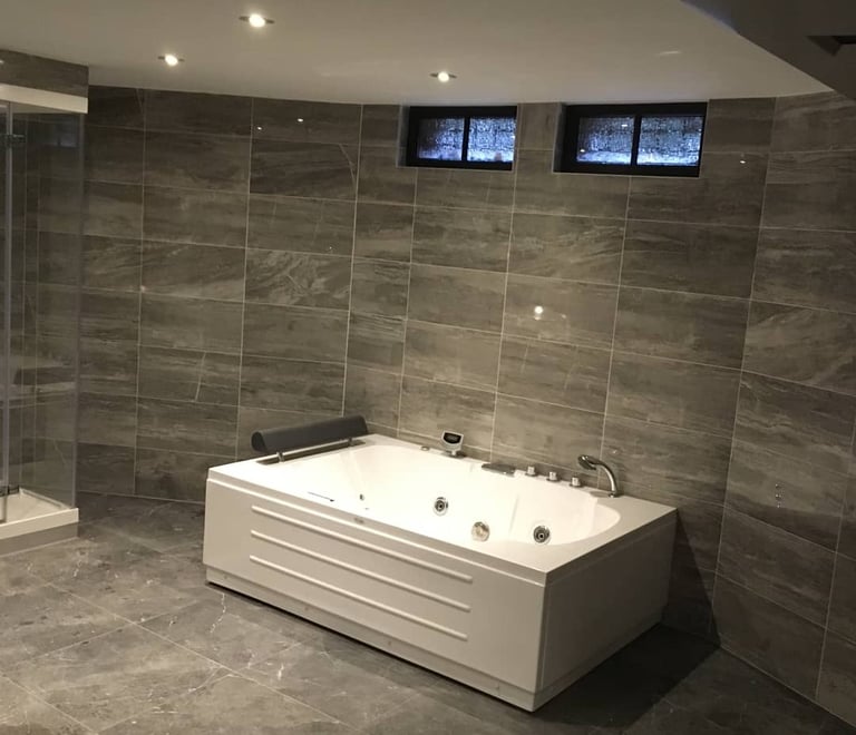 Badkamer met grijs tegels en massagebad 