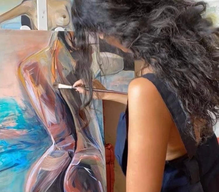 Sherezade Morales painting a captivating woman's silhouette on canvas.