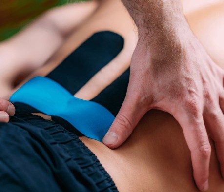 "Un homme recevant une thérapie par bande kinésio sur le dos, avec un thérapeute appliquant la bande adhésive thérapeutique 