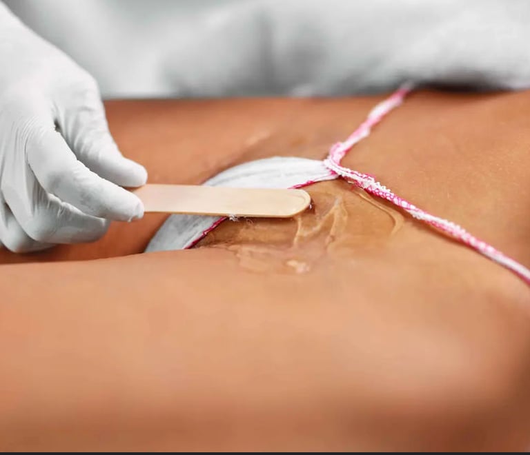 Professional aesthetician applying wax for hair removal treatment on the bikini line