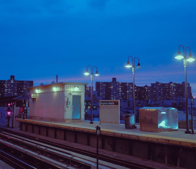 A blue hour shot of a train station, lanterns softly lighting the scene.