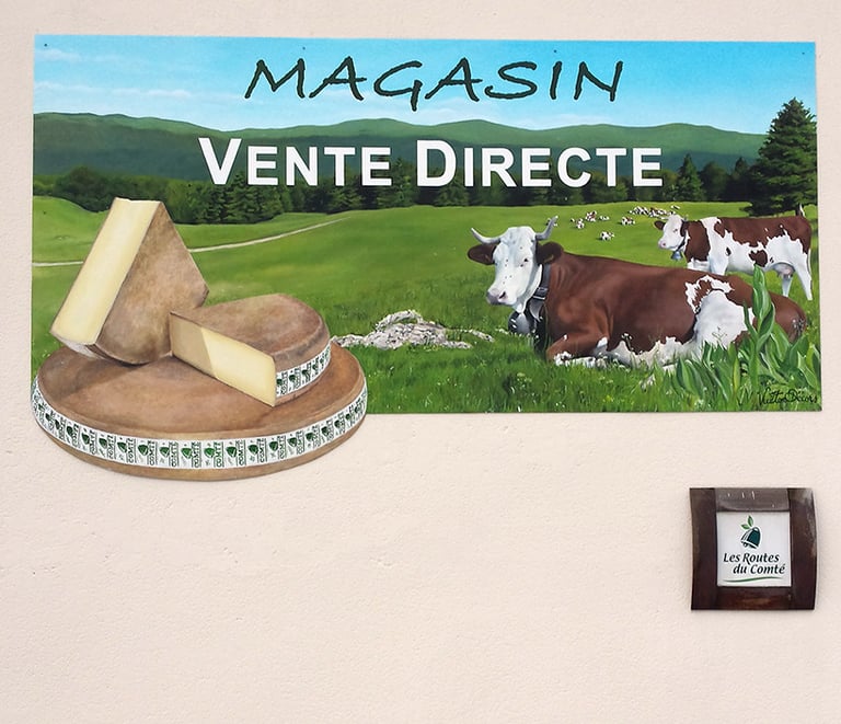 Enseigne peinte du magasin d'une fromagerie à Orgelet (39), Comté, vaches et paysage jurassien.