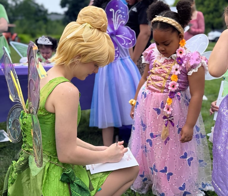 Tinker Bell signs and autograph for a child
