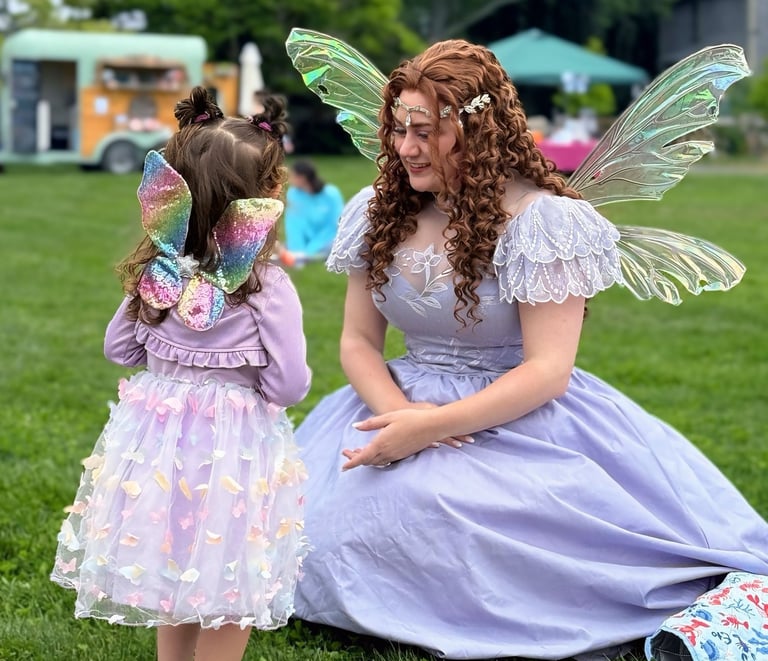 Purple fairy smiles at a kid also dressed as a fairy