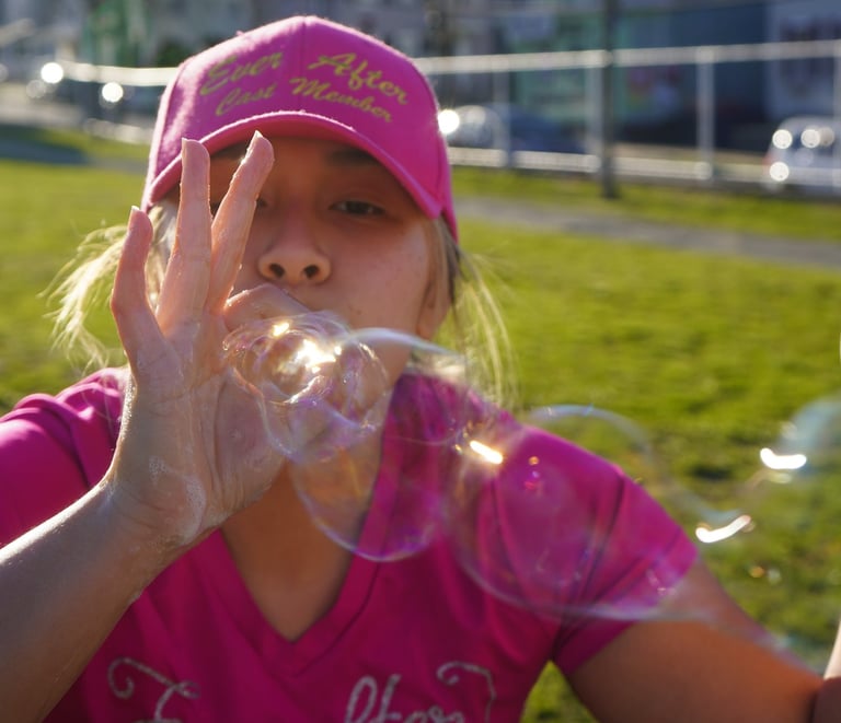 Bubble attendant blows bubbles through their fingers
