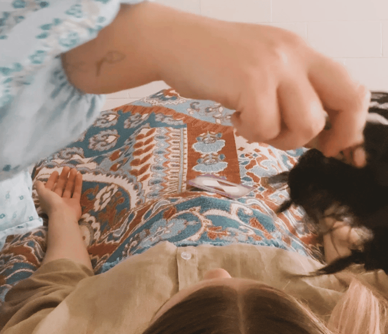 kinesiologist using shamanic rattle for sound healing over client