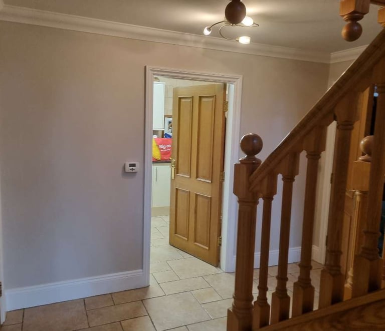 Finished hallway with newly painted walls, wooden staircase, and interior door.