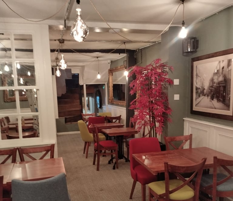Cosy restaurant dining room, with wooden chairs/tables, and fresh grey and white walls/ceiling.