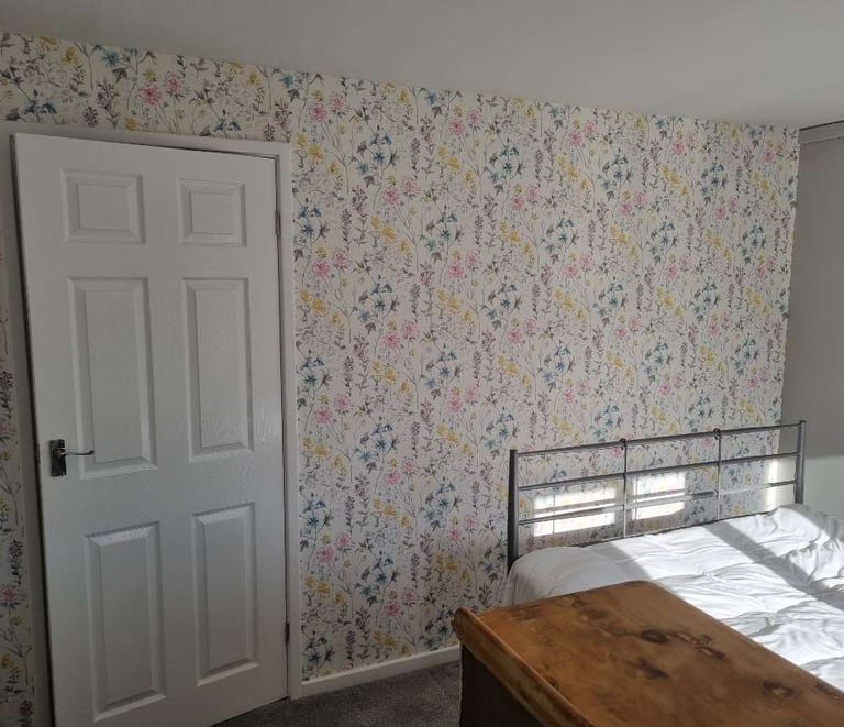 Bedroom wall with bright, botanical wallpaper.