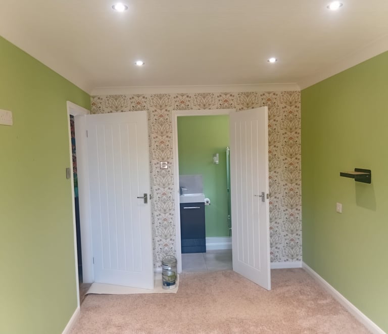 A feature wall with a repeating flower design, and the surrounding walls painted a pale green.