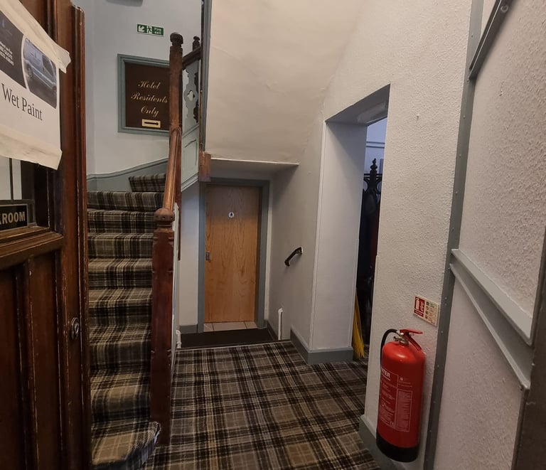 Stairway base with grey, stippled walls and tartan-like floor in a hotel.