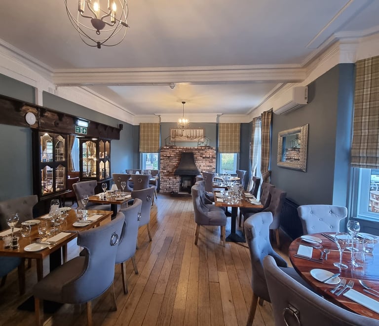 A well-decorated restaurant dining area with a white ceiling, grey walls, and wooden floor.