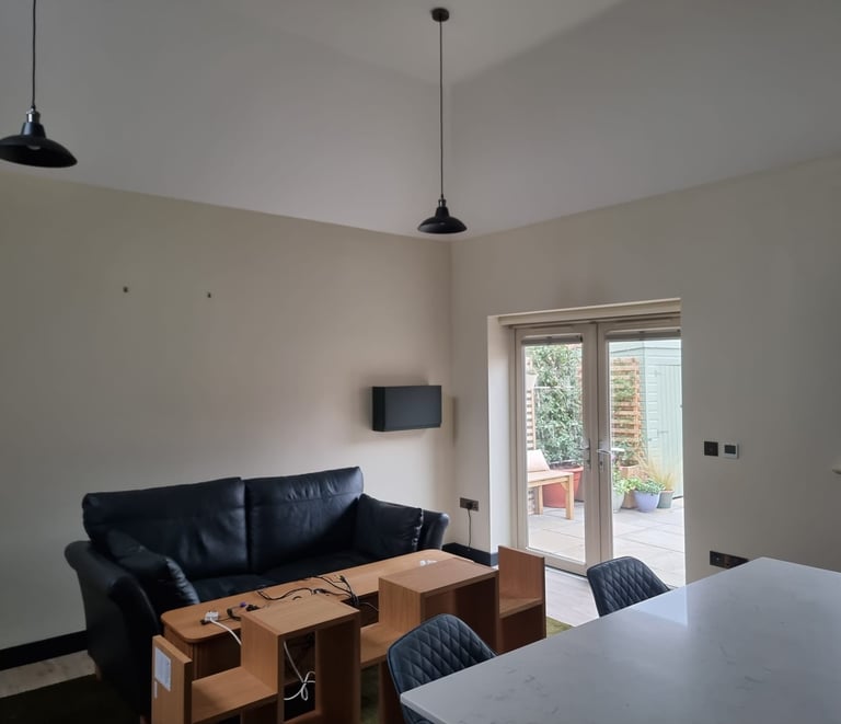 A minimalistic living room, with cream-painted walls and a high, white ceiling.