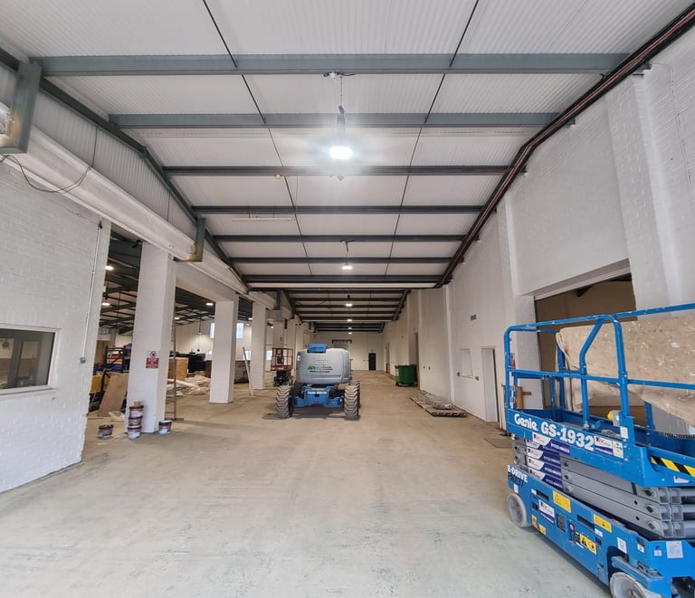 A long, in-use industrial unit, with painted white walls, supports, and ceiling.
