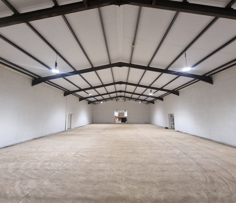 A large industrial unit, completely painted a pure-white with black detailing on the ceiling.
