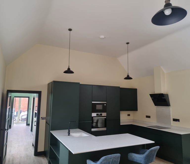 Sleek, modern kitchen with painted-white walls and ceiling, alongside black cupboards/detailing.