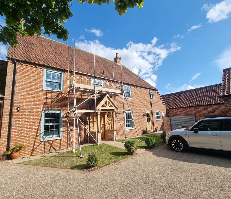 Scaffolding set up on the exterior of a large brick residential house.