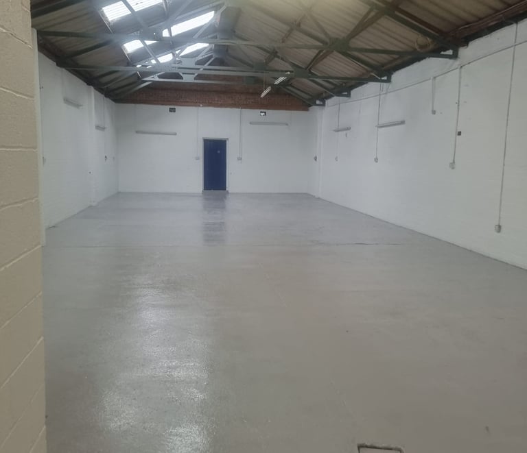 A painted white industrial unit, with a blue door and corrugated roof.