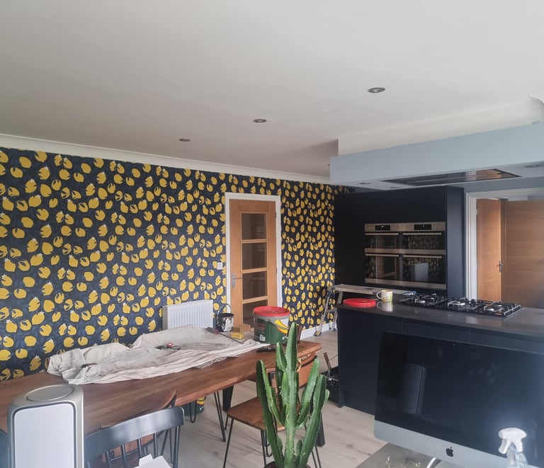 Kitchen in a residential home, with a large wall covered in dark-blue and lemon motif wallpaper.