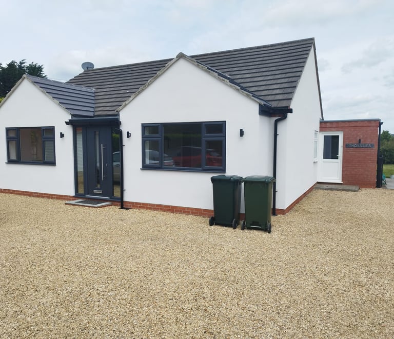 Exterior of a white bungalow with modern-style, black door and windows.