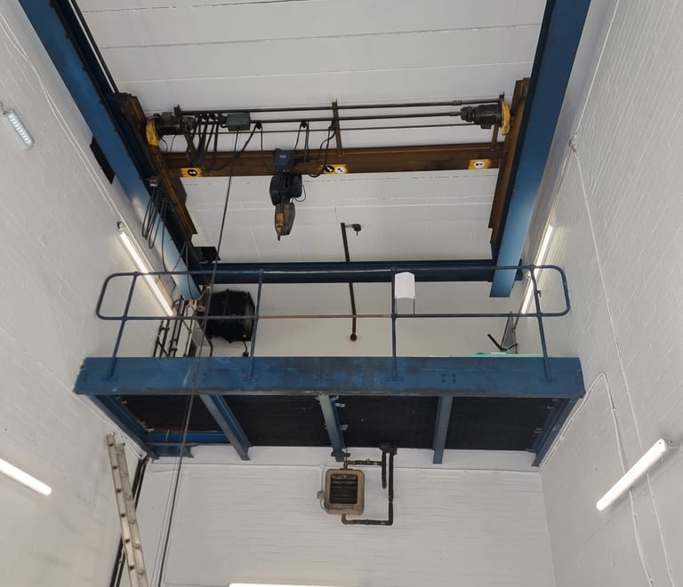 An industrial pure-white, freshly-painted room, with a high ceiling and lift-machinery.