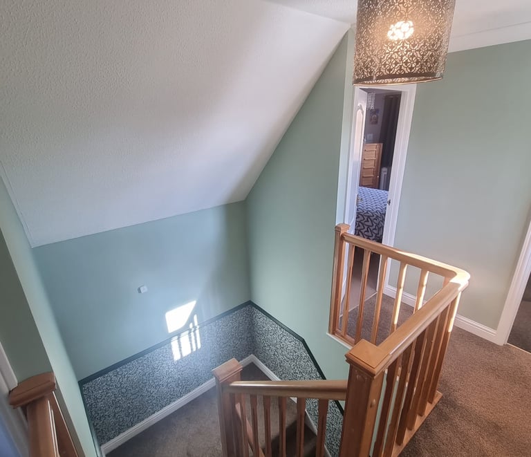 Residential house stairway, with light-green walls halved by static-like wallpaper.