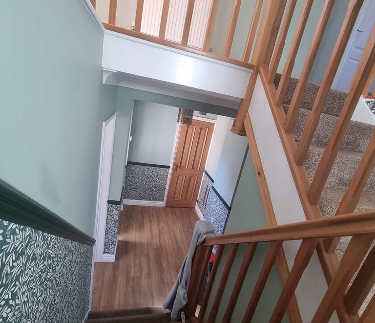 Interior of stairs/hallway from mid-landing, with half grey walls and half dark, floral wallpaper.