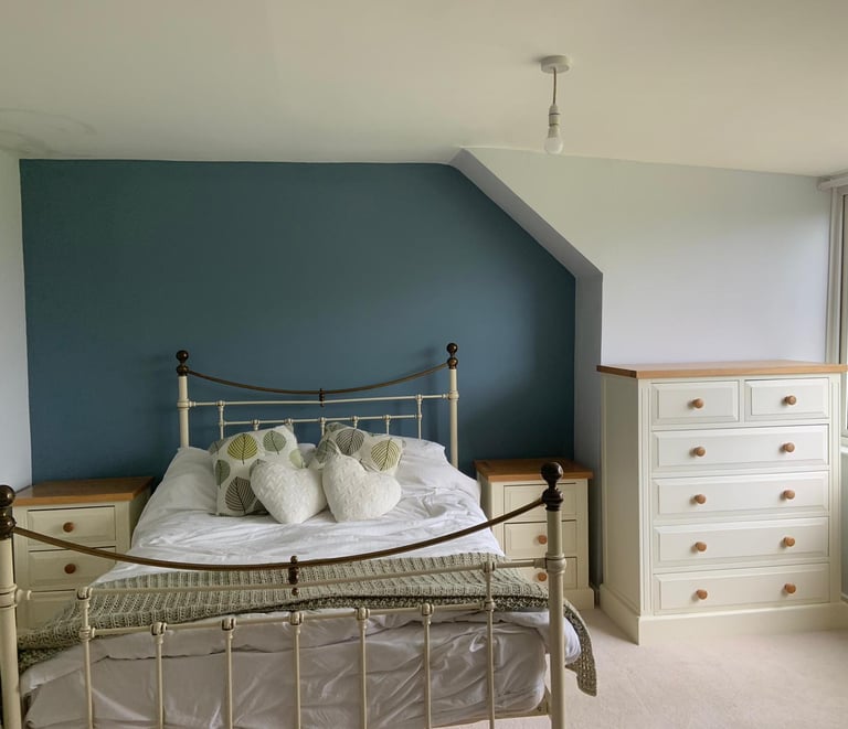 A freshly-painted, tidy bedroom with grey and dark-green walls.