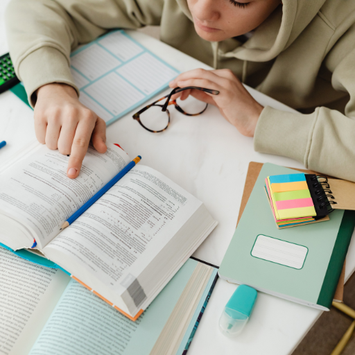 une étudiante sage-femme étant assise avec un livre et des lunettes