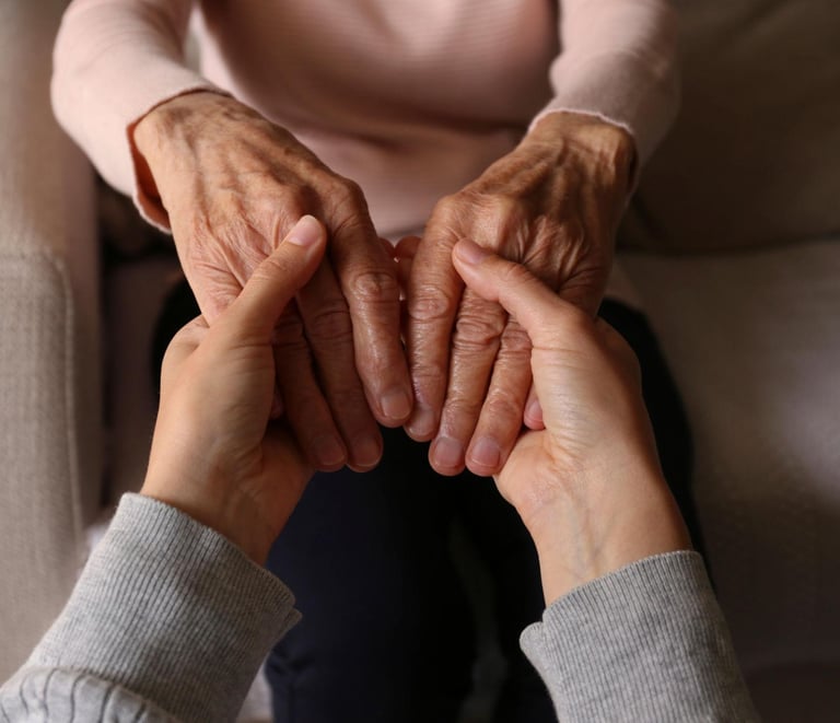 A caregiver's hands gently holding the hands of an elderly woman to show support and senior care.