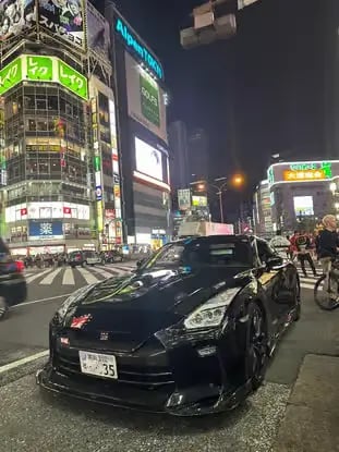 Black Nissan GT-R cruising neon streets of Shibuya, Tokyo.