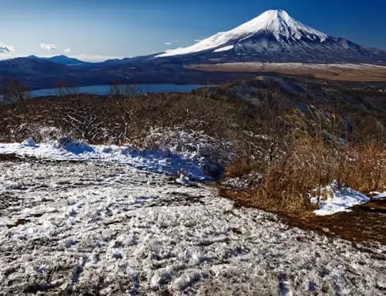 Winter hiking trail near Mt. Fuji with patchy snow on the ground and clear blue skies.
