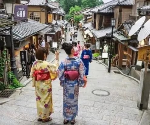 Women in traditional kimono walking up historic stone steps in Kyoto.