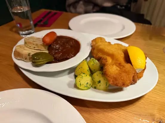 A plate of Wiener Schnitzel, beef goulash, and parsley potatoes.